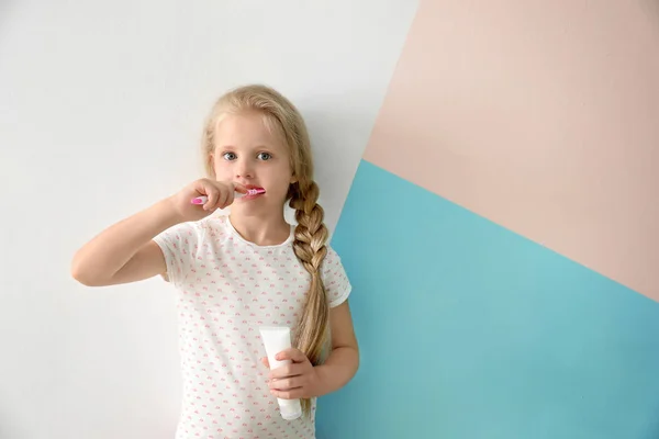 Schattig klein meisje reiniging van de tanden op kleur achtergrond — Stockfoto