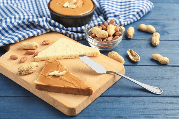 Toasts with delicious peanut butter and nuts on wooden table — Stock Photo, Image