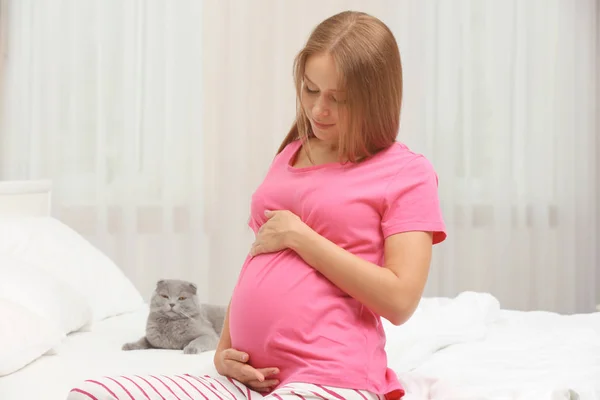 Jovem mulher grávida e bonito gato na cama — Fotografia de Stock