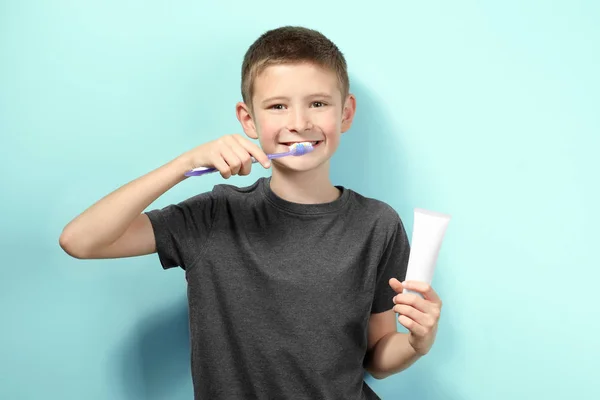 Bonito menino limpando dentes no fundo da cor — Fotografia de Stock