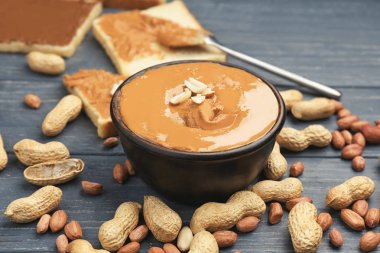 Lezzetli fıstık ezmesi ve ahşap masa üzerinde fındık ile kase