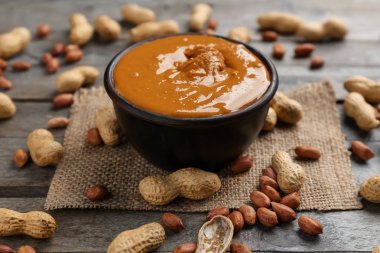 Lezzetli fıstık ezmesi ve ahşap masa üzerinde fındık ile kase