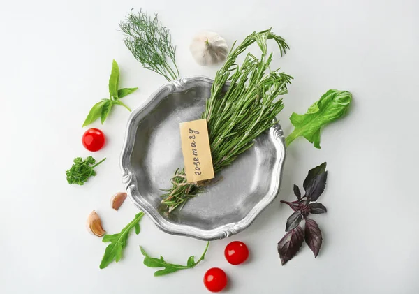 Plaque métallique avec romarin et diverses herbes fraîches sur fond blanc — Photo