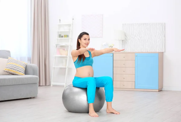 Mujer embarazada joven entrenando en casa. Concepto de salud —  Fotos de Stock