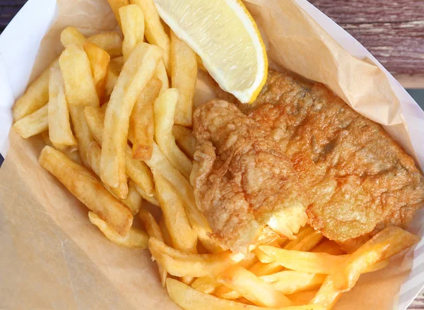 Savoureux poisson frit et frites avec tranche de citron sur fond en bois — Photo