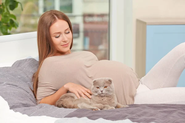 Jovem mulher grávida com gato bonito deitado na cama — Fotografia de Stock