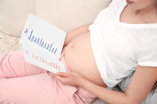 Zwangere vrouw lijst met namen thuis studeren. Concept van het kiezen van de babynaam — Stockfoto