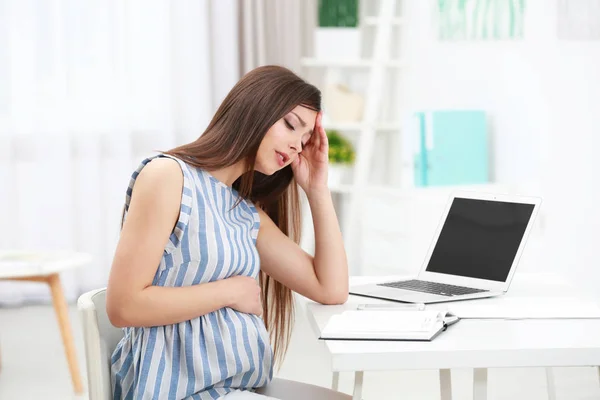 Szép fiatal terhes nő szenved fejfájás, miközben dolgozik a laptop otthon — Stock Fotó
