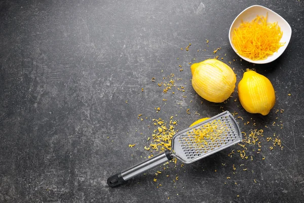 Rallador con ralladura y limones en la mesa —  Fotos de Stock