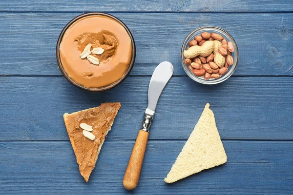 Bowl with delicious peanut butter, nuts and toasts on wooden table — Stock Photo, Image