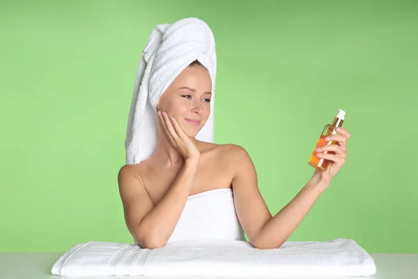 Hermosa mujer joven después del baño con aceite corporal sobre fondo de color —  Fotos de Stock