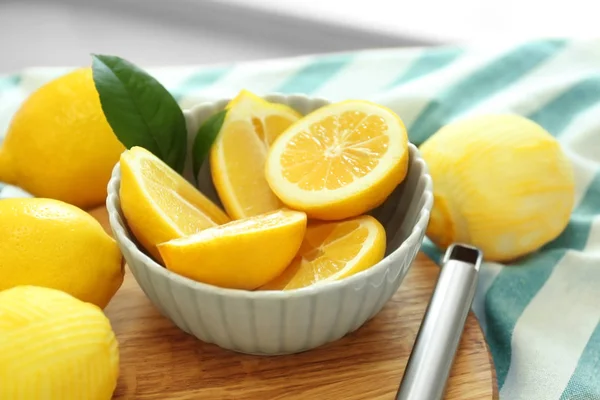 Cuenco con limones en rodajas sobre tabla de madera — Foto de Stock