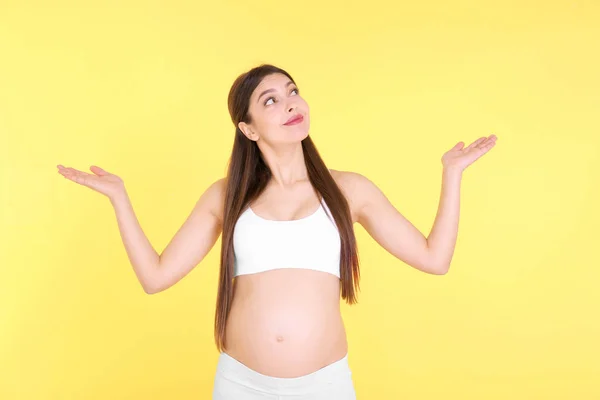 Jovem mulher grávida escolhendo nome para o bebê no fundo amarelo — Fotografia de Stock