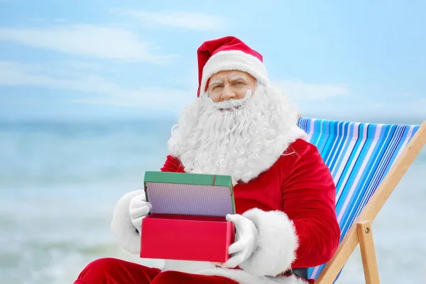 Autentyczny Święty Mikołaj z pudełko w leżak na plaży — Zdjęcie stockowe