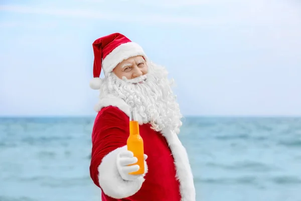 Autentyczny Święty Mikołaj z butelka napoju na tle morza — Zdjęcie stockowe