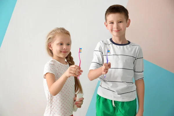 Милі маленькі діти з зубними щітками на кольоровому фоні. Концепція чищення зубів — стокове фото