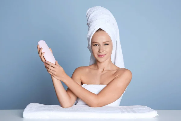 Hermosa mujer joven después del baño con crema corporal sobre fondo claro — Foto de Stock