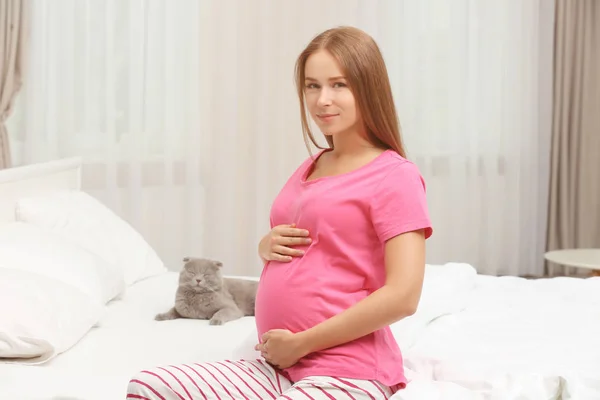 Wanita hamil muda dan kucing lucu di tempat tidur — Stok Foto