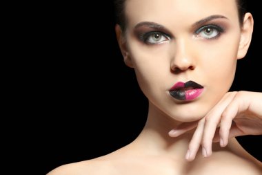 Güzel genç kadın koyu arka plan üzerinde yaratıcı makyaj ile