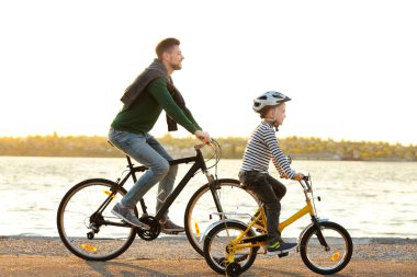 Baba ve oğul yakınındaki su açık bisiklet sürme