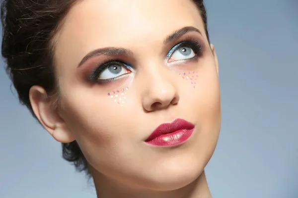Hermosa mujer joven con maquillaje creativo en el fondo de color, primer plano — Foto de Stock