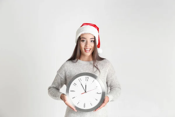 Noel Baba şapkası ile masa saati içinde genç kadın — Stok fotoğraf