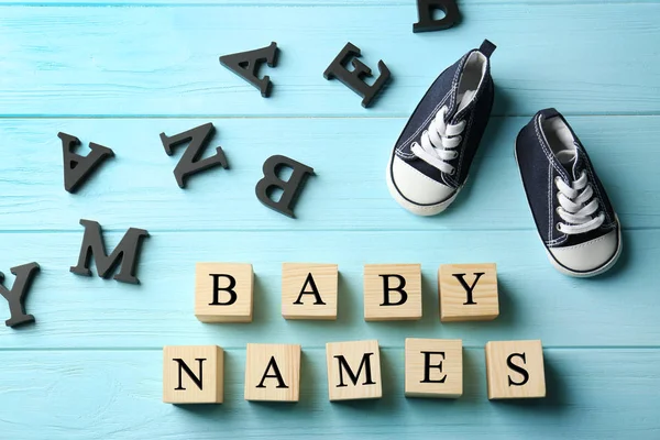 Holzwürfel mit Text Babynamen und Schuhe auf farbigem Hintergrund — Stockfoto