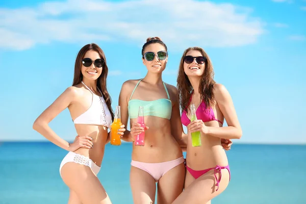 Beautiful young women in bikini with alcoholic drinks at sea resort — Stock Photo, Image