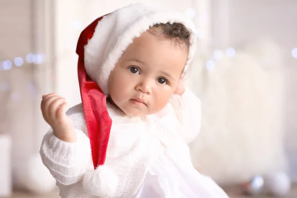 可爱的小宝宝，在圣诞老人的帽子，对模糊的圣诞灯 — 图库照片