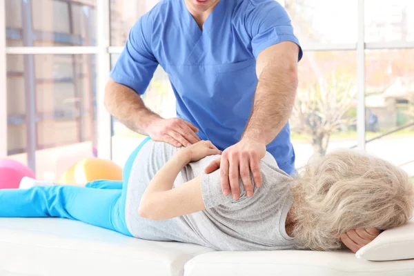 Fysiotherapeut werken met oudere patiënt in kliniek — Stockfoto