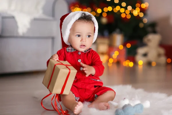 Schattige kleine baby met kerstman hoed en gift box in ingericht voor Kerstmis kamer — Stockfoto