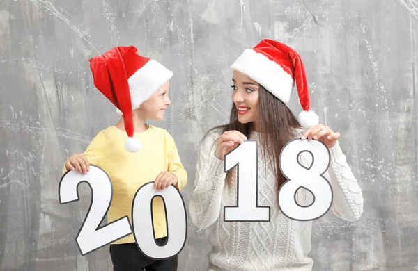 Mujer joven y linda niña con figuras de papel 2018 sobre fondo grunge. Concepto de celebración de Navidad —  Fotos de Stock