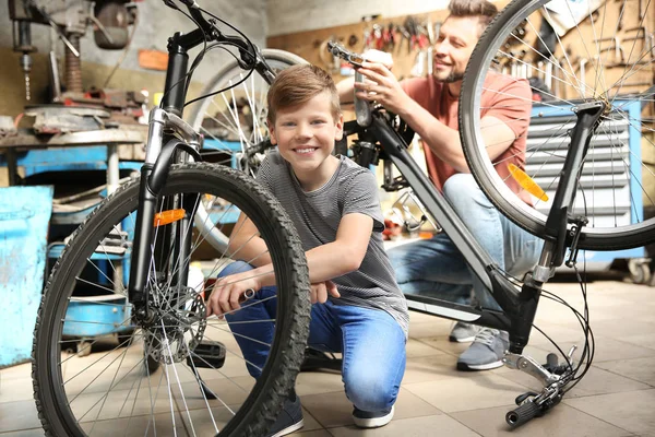 お父さんと息子のガレージに自転車を固定 — ストック写真