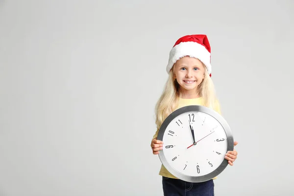 Petite fille mignonne dans le chapeau de Père Noël avec horloge — Photo