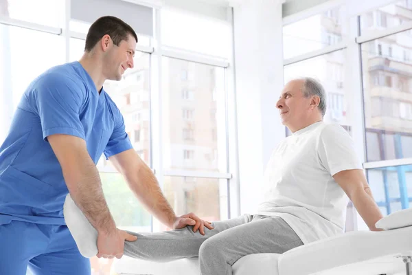 Fisioterapista che lavora con pazienti anziani in clinica — Foto Stock
