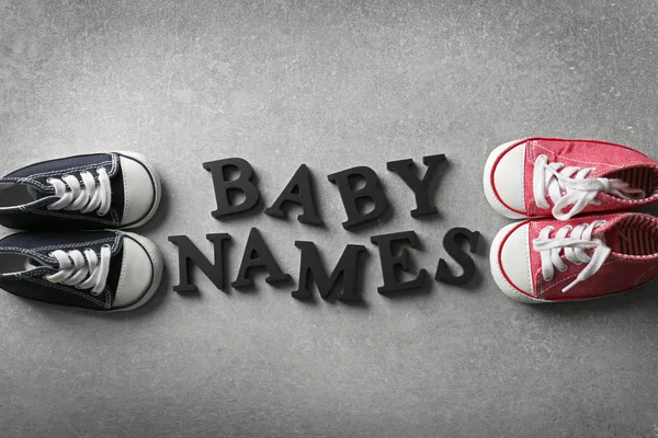 Texto BABY NAMES e sapatos em fundo cinza — Fotografia de Stock