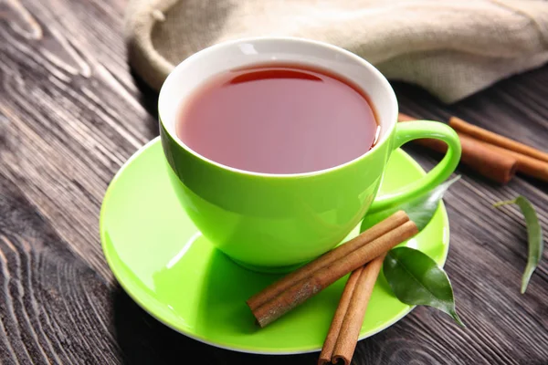 Cup of delicious tea and cinnamon on table — Stock Photo, Image