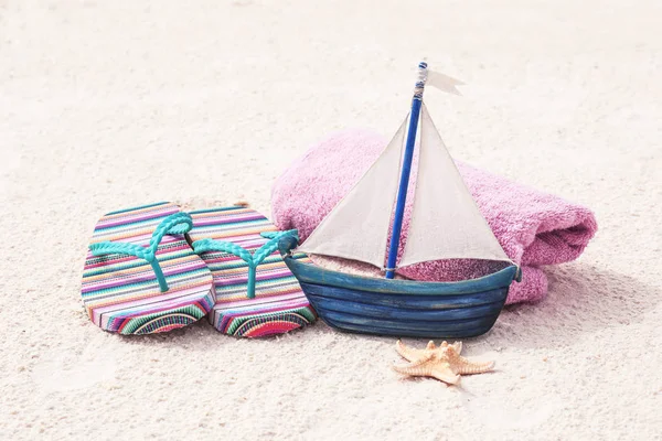 Navio de brinquedo com chinelos na areia — Fotografia de Stock