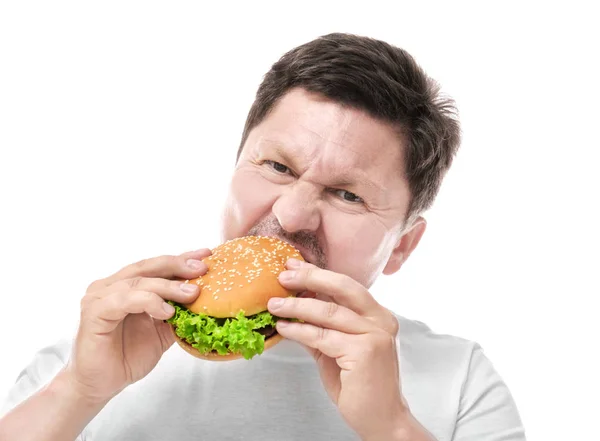 Un om supraponderal mănâncă burger pe fundal alb. Conceptul de dieta — Fotografie, imagine de stoc