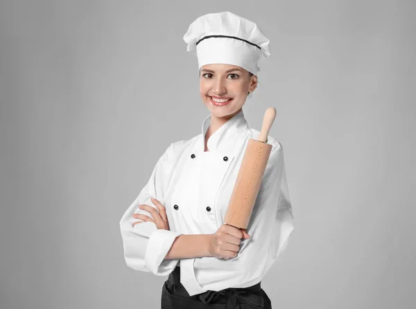 Jovem chef feminino com rolo de pino no fundo claro — Fotografia de Stock