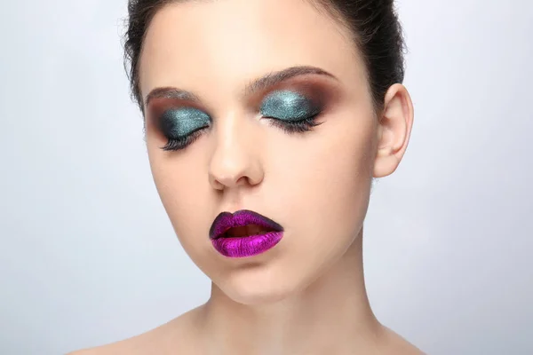 Mooie jonge vrouw met creatieve make-up op lichte achtergrond — Stockfoto