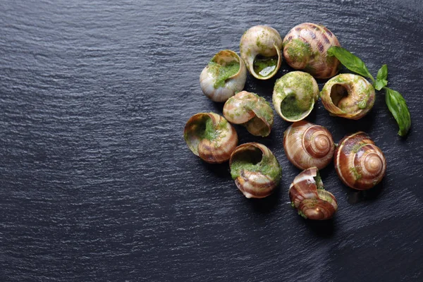 Delicious snails in green sauce on dark table — Stock Photo, Image