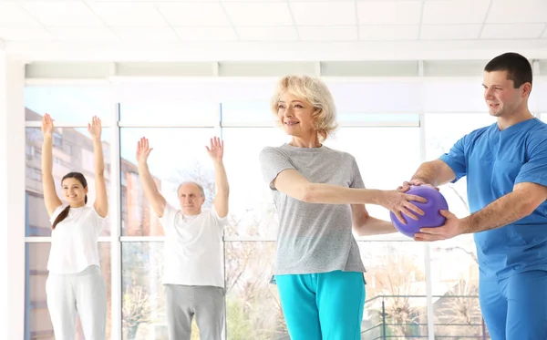 Physiotherapeut arbeitet mit älteren Patienten in moderner Klinik — Stockfoto