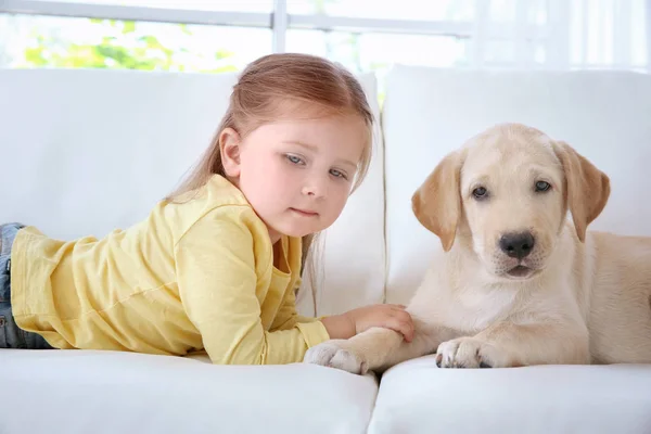 Niedliches Kind mit Labrador Retriever auf dem Sofa — Stockfoto