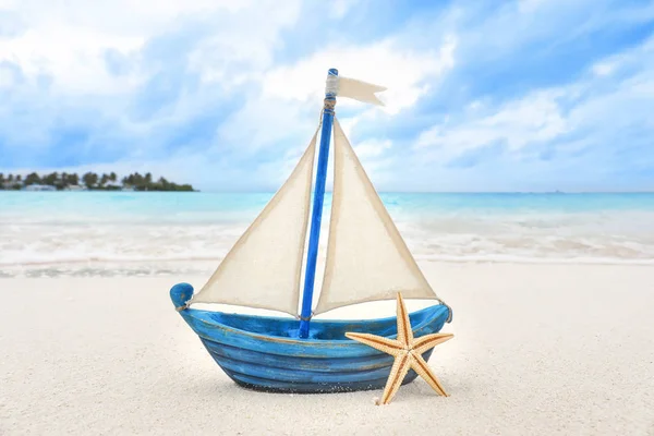 Small toy ship and starfish on beach — Stock Photo, Image