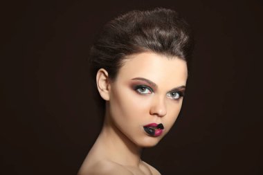 Güzel genç kadın koyu arka plan üzerinde yaratıcı makyaj ile
