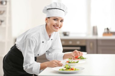 Genç bayan aşçı mutfakta yemek pişiriyor.