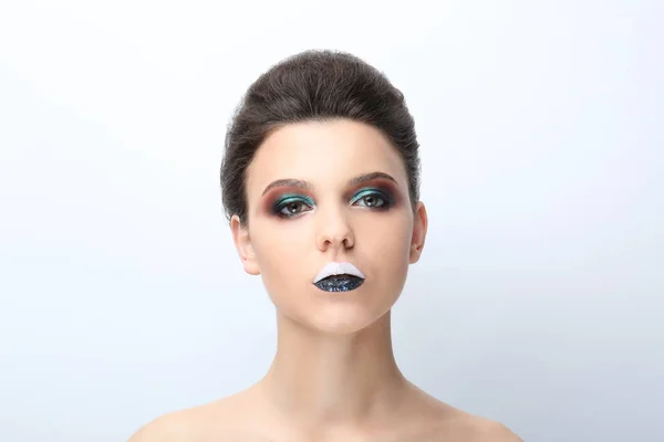 Mooie jonge vrouw met creatieve make-up op lichte achtergrond — Stockfoto