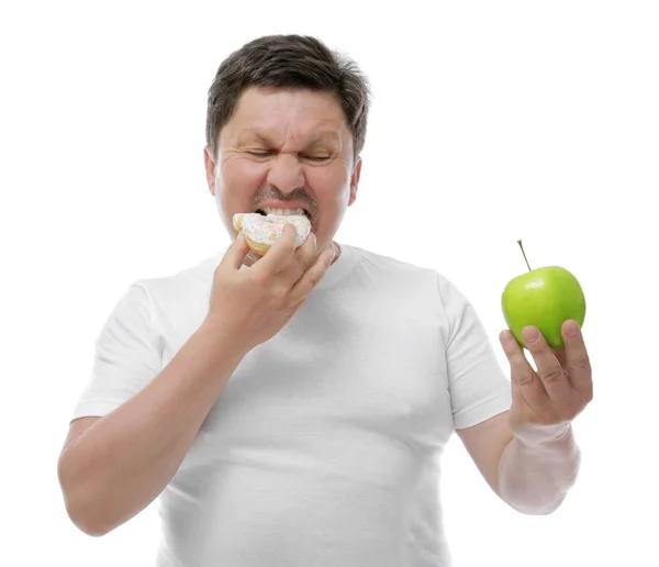 Людина з надмірною вагою з яблуком і пончиком на білому тлі. Концепція дієти — стокове фото