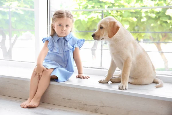 Niedliches Kind mit Labrador-Retriever auf Fensterbank zu Hause — Stockfoto